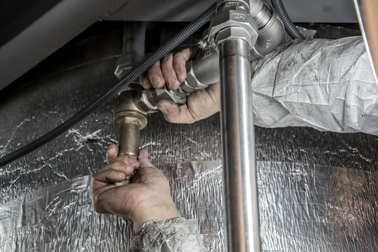 Technician repairing a pipe under a sink